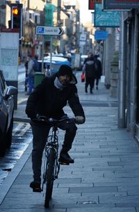Rear view of man riding bicycle on street in city