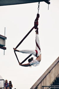 Low angle view of man hanging on clothesline against sky