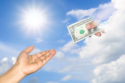 Low angle view of hand holding umbrella against sky