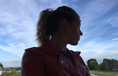 Portrait of young woman looking away against sky