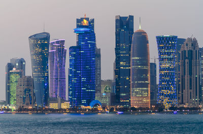 Illuminated buildings in city against sky