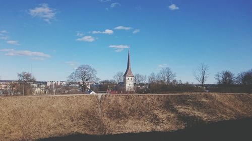 Traditional windmill by bare trees against sky