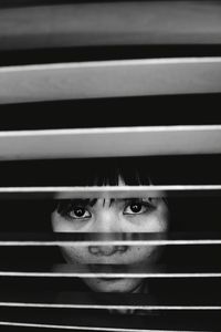 Portrait of woman seen through blinds