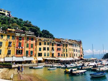 Boats moored by buildings in city against clear sky