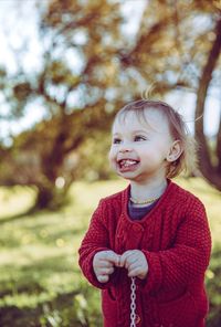 Smiling girl chewing bubble gum against tree