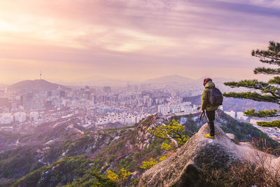 Man standing on city against cloudy sky