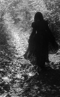 Rear view of woman standing in forest