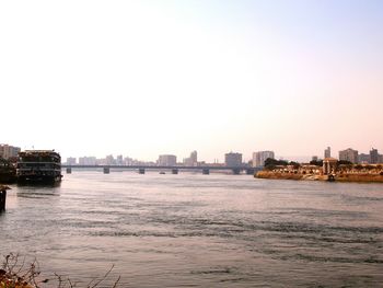 Buildings by river against clear sky