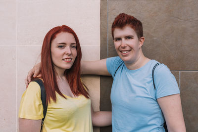 Portrait of female friends against wall