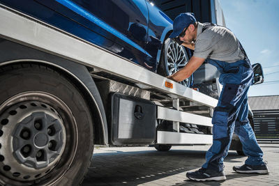 Tow truck driver preparing to safely deliver brand new car from dealer to buyer. 