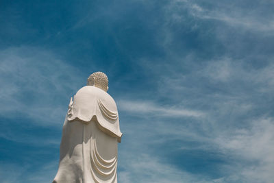 Low angle view of buddha statue against blue sky