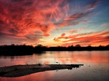 Scenic view of lake against dramatic sky during sunset