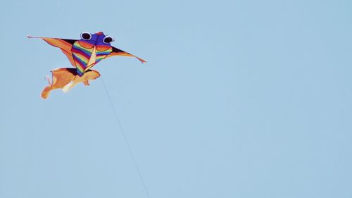 Low angle view of kite against clear blue sky