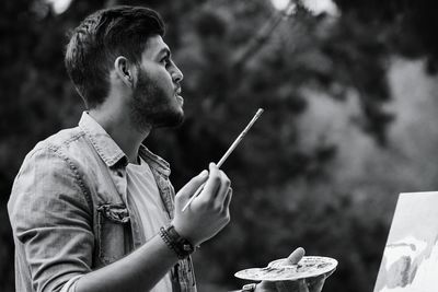 Painter looking up while holding paintbrush and palette