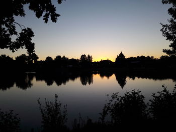 Silhouette trees by lake against sky during sunset