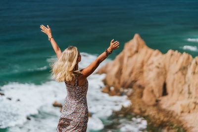 Woman standing on cliff against sea