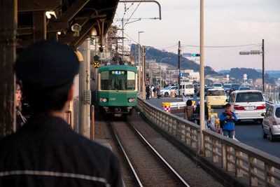 Rear view of woman at railroad station against sky