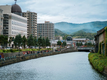 River by buildings in city against sky