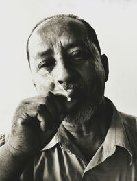 Close-up portrait of mature man smoking against white background