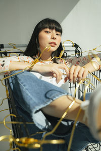 Portrait of young woman sitting in shopping cart