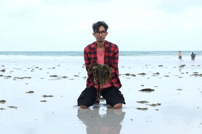 Portrait of young man on beach against sky