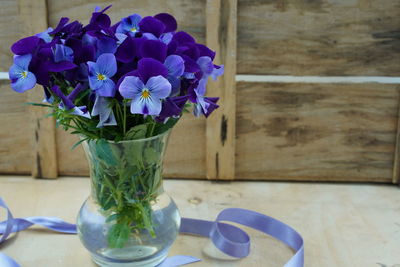 Close-up of purple flower vase on table. pansies flower bouquet in clear glass.