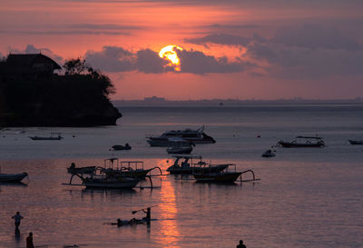 Boats in calm sea at sunset