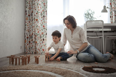 Joint game of mom and son at home, build houses from a wooden constructor. concept childhood 
