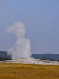 Steam emitting from volcanic landscape against clear sky