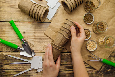 Women's hands hold peat pots. top view of seeds and garden tools on a wooden background.