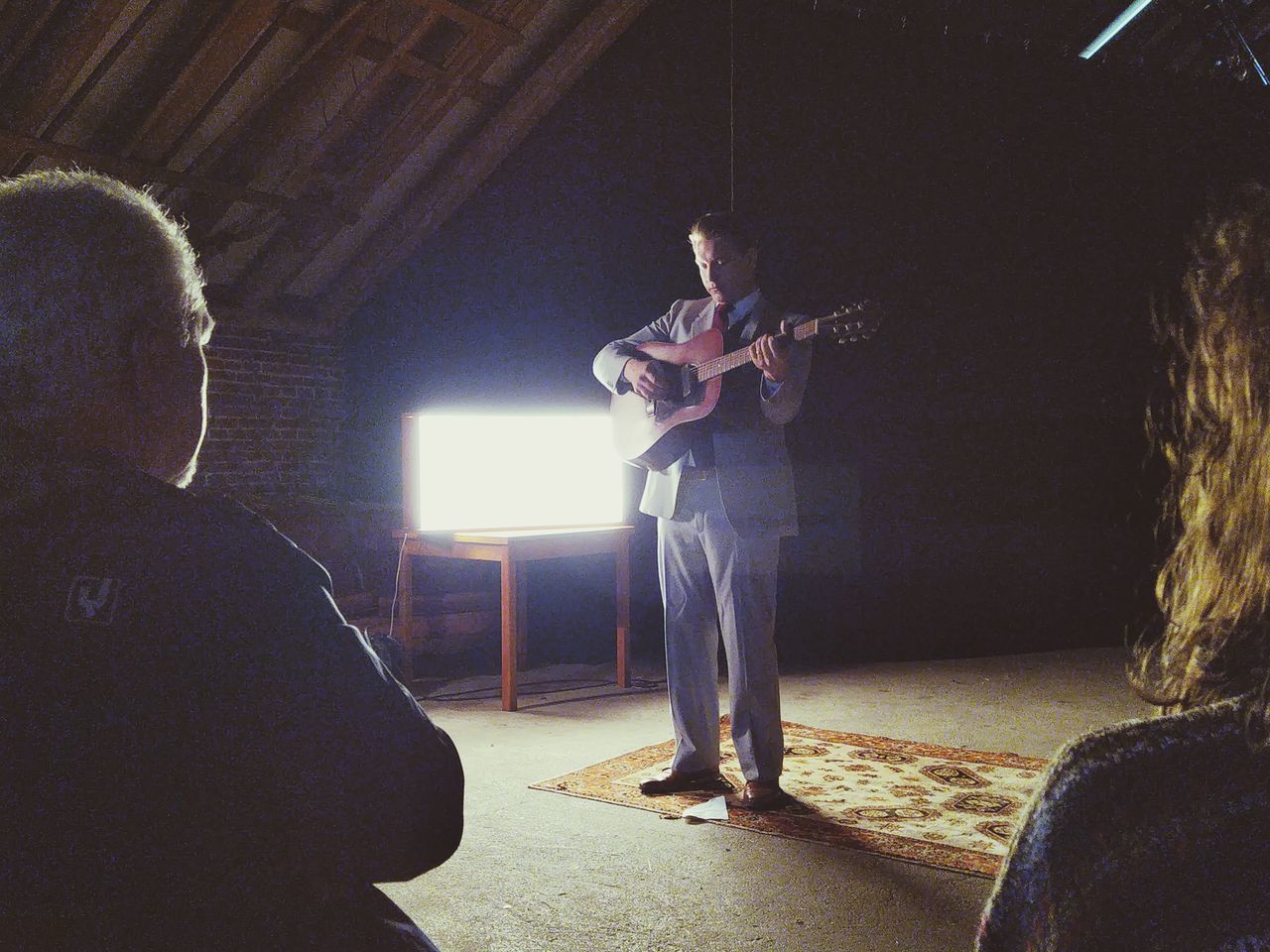 PEOPLE PLAYING GUITAR AT ILLUMINATED STAGE