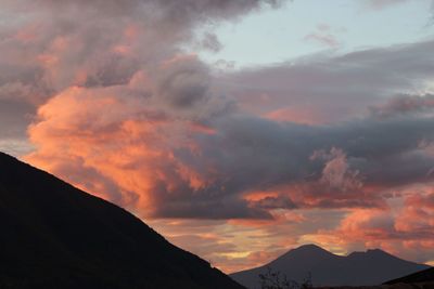 Low angle view of silhouette mountains against orange sky