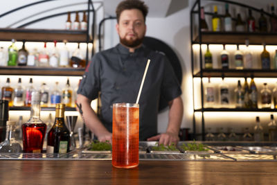 A glass of delicious red alcohol drink with a cocktail tube on a bar counter. night club drink.