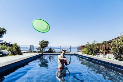 Rear view of man in swimming pool against sky