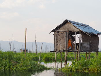 House by lake against sky