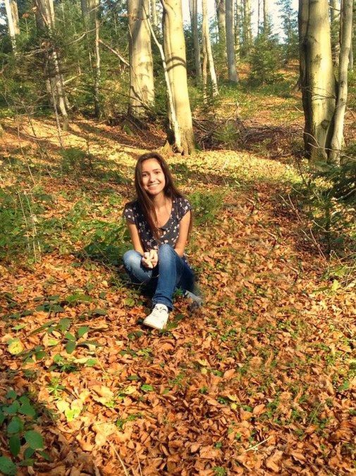 person, young adult, looking at camera, tree, lifestyles, forest, portrait, leisure activity, casual clothing, young women, front view, smiling, tree trunk, standing, leaf, full length, happiness, autumn