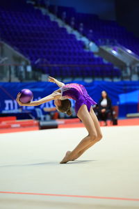 Girl gymnast performs an exercise with a ball