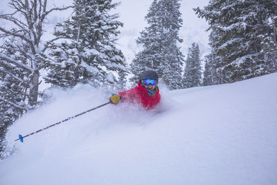 Cheerful woman skiing on snow covered landscape