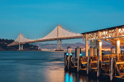 Illuminated bridge against clear blue sky