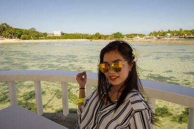 Portrait of young woman in sunglasses against sea