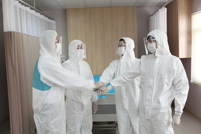 Surgeons stacking hands while standing in hospital