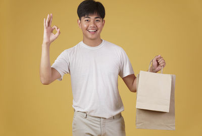 Portrait of smiling boy standing against yellow background