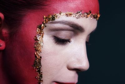 Close-up portrait of a young woman over black background