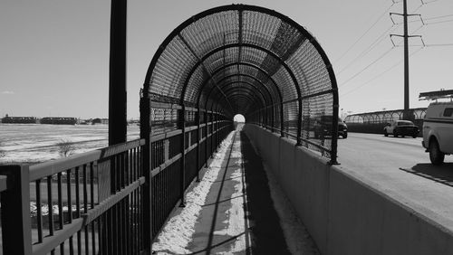 Covered walkway by road against clear sky