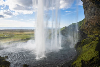 Close-up of seljalandsfoss waterfall flowing from mountain against blue sky