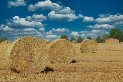 Hay bales on field against sky