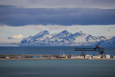 Scenic view of sea and snowcapped mountains against sky