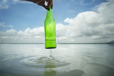 Green bottle on sea against sky