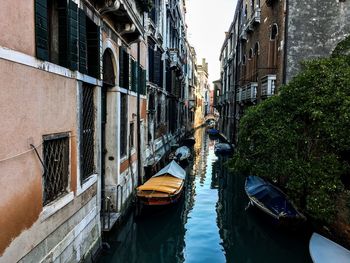 Boats moored in canal amidst buildings