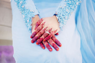 Midsection of bride with henna tattoo sitting on seat